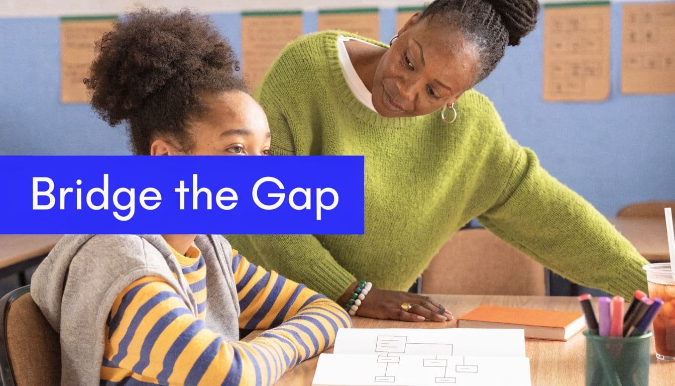 A teacher in a green sweater assisting a young student with school work at a classroom desk.