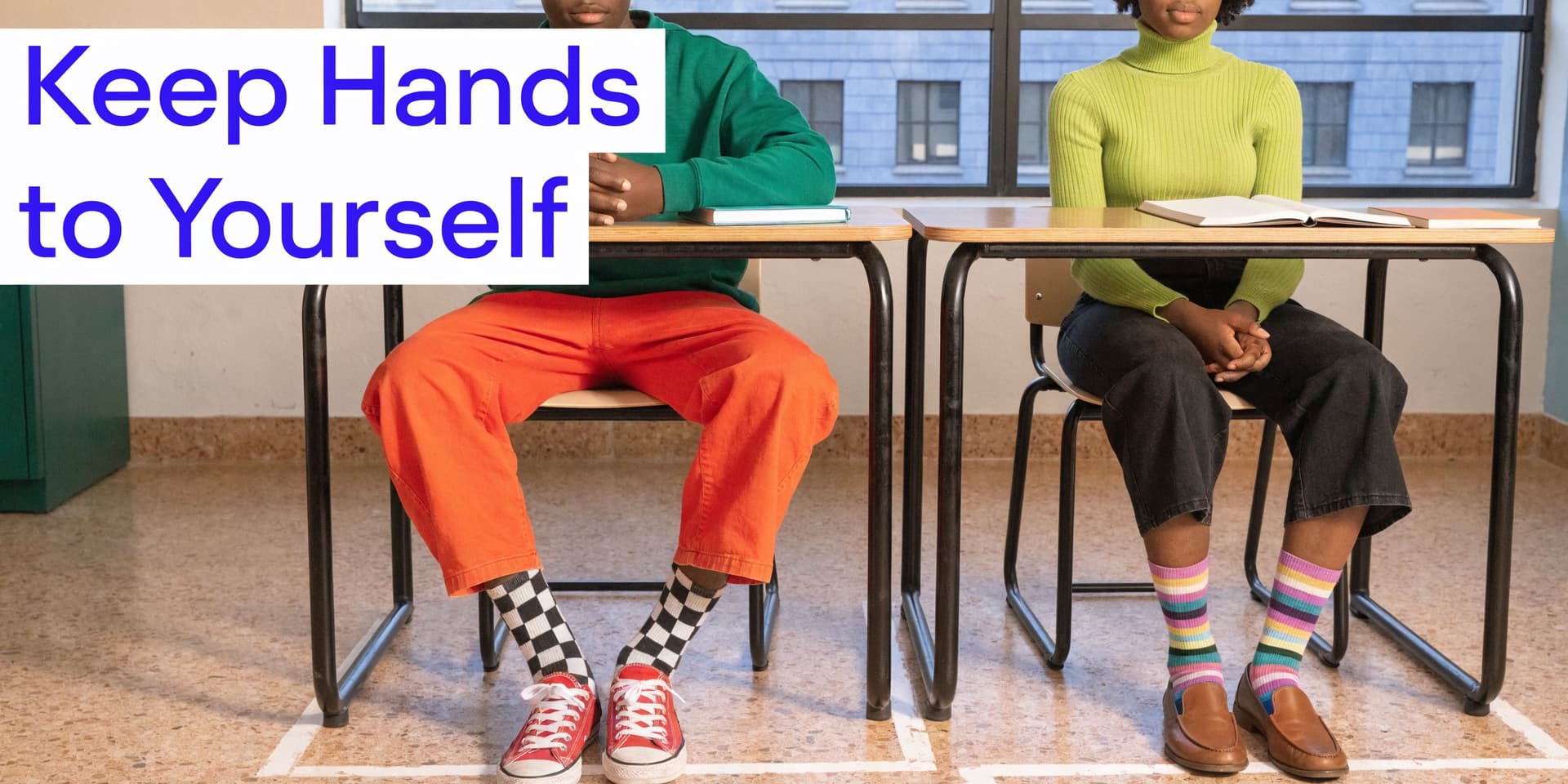 Two students sitting at separate desks in a classroom, illustrating the importance of personal space and boundaries.