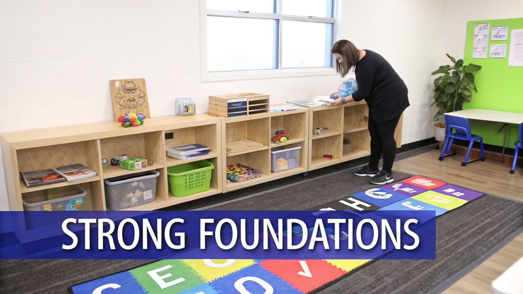 A teacher organizes a classroom with wooden shelves, educational materials, and a colorful alphabet rug.